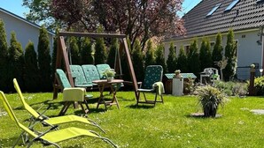 Un jardin avec une balançoire, une table et des chaises, et un pot de fleurs.