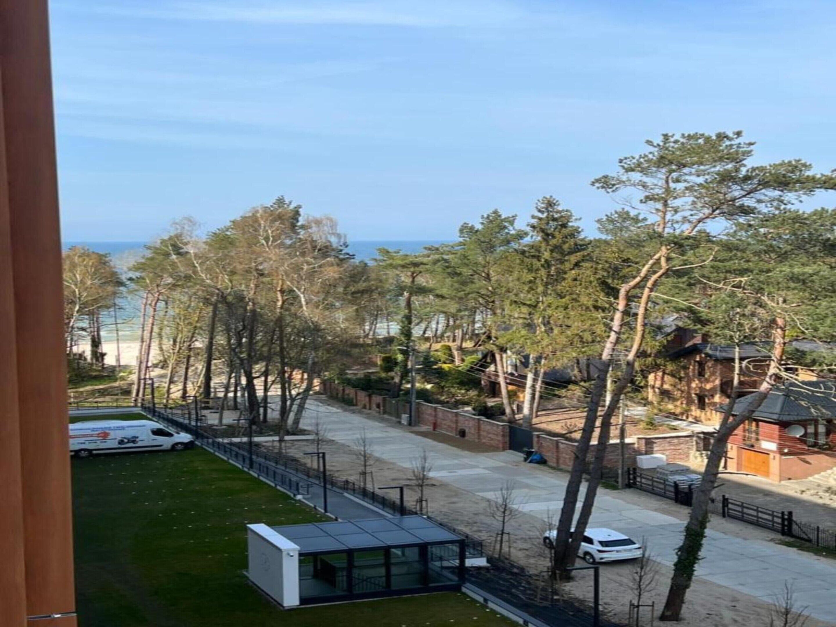 Vista de una zona residencial con un edificio moderno, un sendero y una playa al fondo.