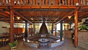A restaurant with a central fountain, wooden ceiling beams, brick flooring, and wooden tables and chairs. - Apartment in Montaione With Carport (Montalcino)