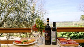 A table with a plate of food, a glass of wine, and two bottles of wine. - Apartment in Montaione With Carport (Montalcino)