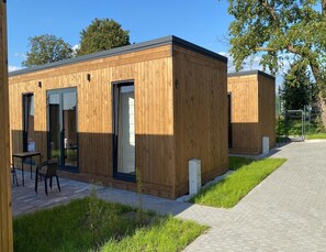 En modern stuga i trä med en uteplats, inklusive ett bord och stolar.