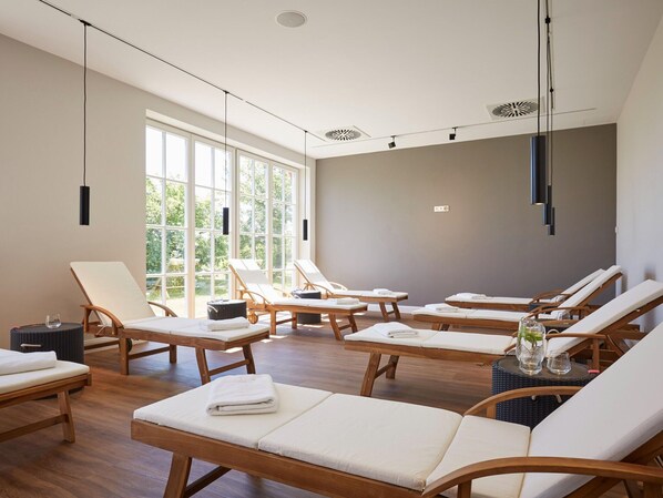 A spa room with wooden loungers, large windows, and ceiling lights. - Apartment in Dranske With Pool (Dranske)