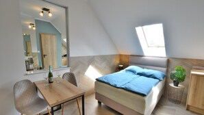 A bedroom with a bed, a bedside table, a chair, a mirror, and a window. - Comfortable, 2-person Holiday Studio (Ustronie Morskie)