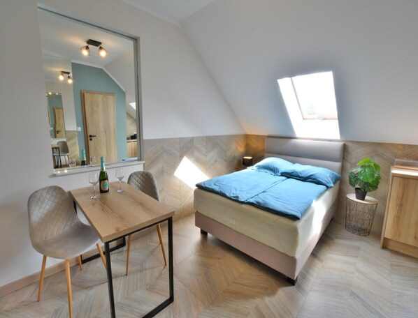 A bedroom with a bed, a bedside table, a chair, a mirror, and a window. - Comfortable, 2-person Holiday Studio (Ustronie Morskie)