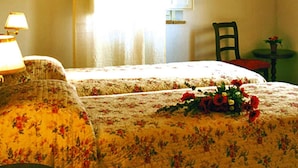 Una stanza con un letto, una sedia, un tavolo e una finestra con tende.