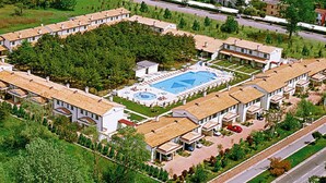 Vue aérienne d’un complexe hôtelier comprenant plusieurs bâtiments, une piscine et une pelouse bien entretenue.