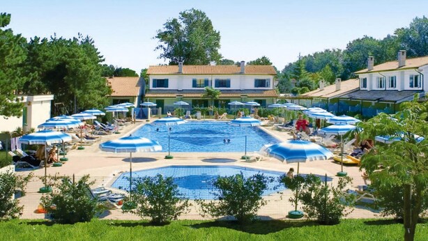 Une piscine avec plusieurs couloirs de nage, entourée de chaises longues et de parasols.