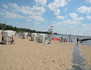 A beach with beach chairs, a lifeguard tower, and a pier. - Holiday Home in Stepnica by Szczecin Lagoon (Stepnica)