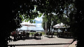Eine Außenpatio-Terrasse mit sechseckigem Pflaster, Tischen, Stühlen und Sonnenschirmen.