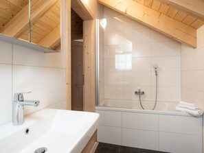 Un baño moderno con una bañera independiente, ducha con mampara de vidrio y un espejo grande sobre el lavamanos.