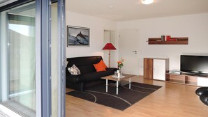 A modern living room with a black leather sofa, a coffee table, a TV, and a red lamp. - Modern Flat in Messstetten Town (Messstetten)