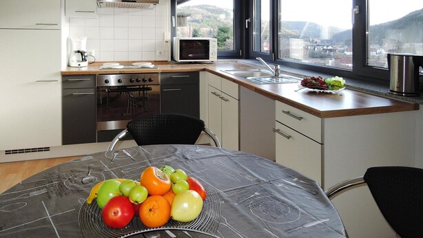 A modern kitchen with a microwave, stove, and sink. A fruit bowl is on the table, and there's a window with a view of the outdoors. - Modern Flat in Messstetten Town (Messstetten)