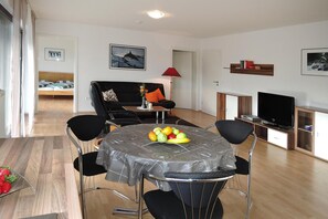 A modern living room with a dining table, chairs, a sofa, a TV, and a fruit bowl. - Modern Flat in Messstetten Town (Messstetten)