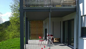 A modern building with a covered patio area featuring a table and chairs. - Modern Flat in Messstetten Town (Messstetten)