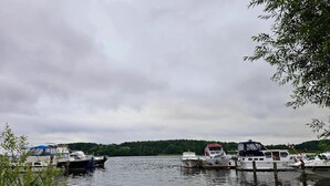 A calm lake with several boats docked, surrounded by greenery and overcast skies. - Ferienwohnungen, Malchow (Malchow)