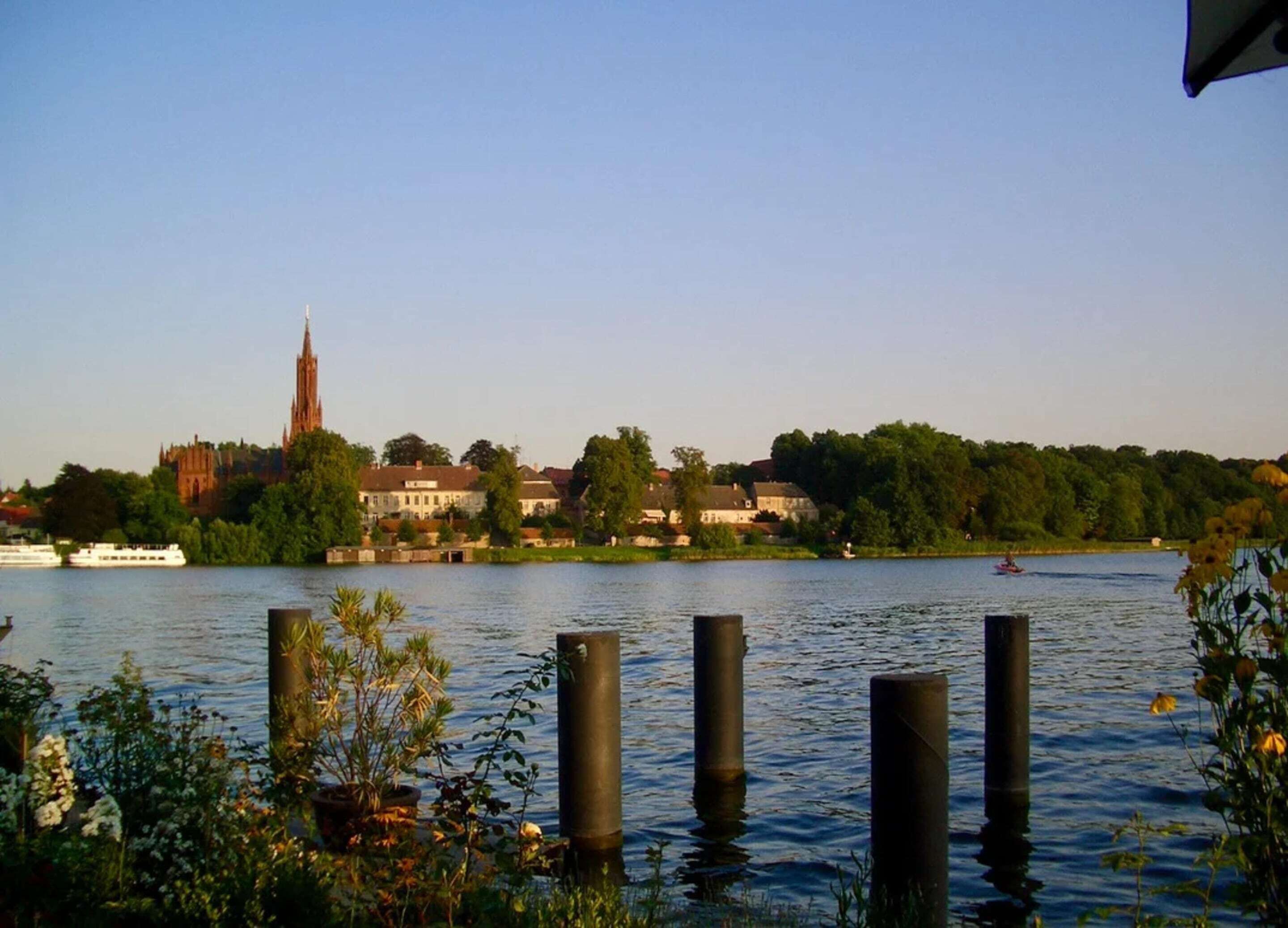 A river with a church and residential buildings in the background.