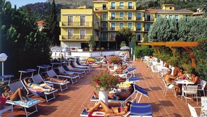 A rooftop pool area with sun loungers and a bar, surrounded by buildings and hills. - Apartment in Pietra Ligure With Garage (Pietra Ligure)