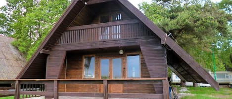 Une cabane en bois avec un toit en pente, un balcon et une véranda à l’avant.
