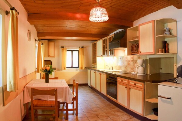 A kitchen with wooden cabinets, a dining table with chairs, a chandelier, and a window with curtains. - Farmhouse Near Afritzer See & Nockberge Trails (Treffen)