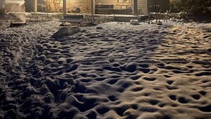 Paisaje nevado con una cabaña de madera que tiene un amplio porche y una chimenea.