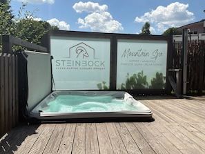 Et spabad på en træterrasse med et skilt for Steinbock Alpine Luxury Chalet og Mountain Spa.