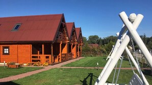 Eine Holzhütte mit rotem Dach, einer Veranda und einem gepflegten Rasen.