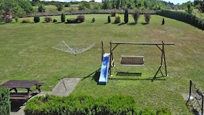 A playground with a slide, swing set, and picnic table in a grassy park area. - Holiday Home in Lubin Near Wollin Park (Międzyzdroje)