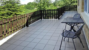 A balcony with a tiled floor, a metal table and chairs, and a wooden fence. - Holiday Home in Lubin Near Wollin Park (Międzyzdroje)