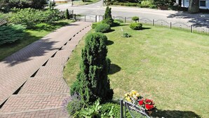 A residential street with a paved walkway, neatly trimmed hedges, and a variety of flowering plants. - Holiday Home in Lubin Near Wollin Park (Międzyzdroje)