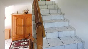 A staircase with a wooden handrail and white tiled steps leading to a landing. - Holiday Home in Lubin Near Wollin Park (Międzyzdroje)