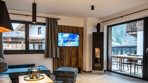 Un salon moderne doté d’un téléviseur, de touches de décoration en bois, d’un canapé et offrant une vue à travers de grandes portes coulissantes.