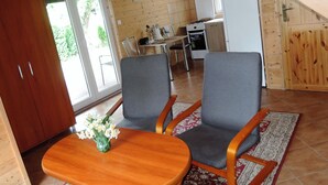 A wooden interior with a dining area, kitchen, and a large wooden door. - Holiday Home in Miedzyzdroje Near Baltic Sea (Międzyzdroje)
