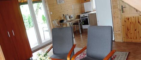 A wooden interior with a dining area, kitchen, and a large wooden door.
