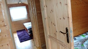 A wooden interior with a door, a window, and a bed with patterned bedding. - Holiday Home in Miedzyzdroje Near Baltic Sea (Międzyzdroje)
