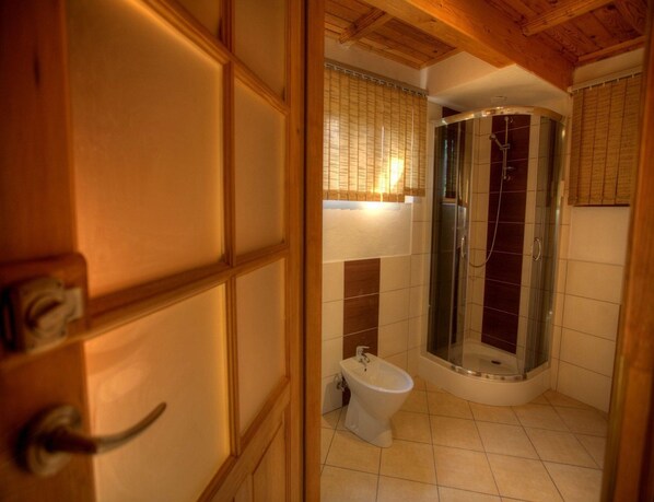 A bathroom with a shower, toilet, and bidet.