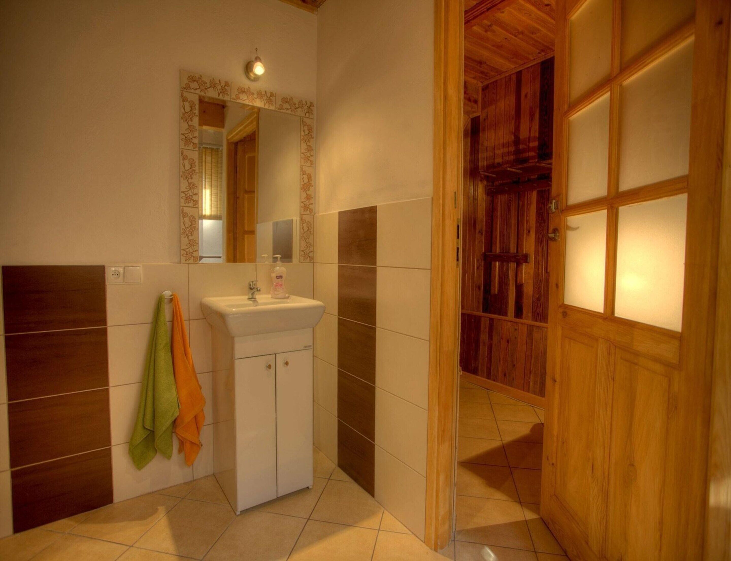 Un baño con lavamanos, espejo y puerta de madera.