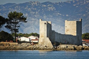 A historic stone castle with two towers, situated by a body of water with mountains in the background. - Apartment on Vir Island Near Pebble Beaches (Vir)