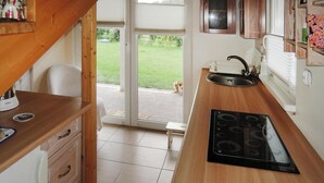 A kitchen with wooden cabinets, a black stove, and a sink. - Holiday Home on Lake Ostrowo Near Baltic Sea (gmina Wolin)
