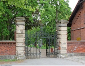 A gated entrance with a brick wall and a metal gate. - Holiday Home on Lake Ostrowo Near Baltic Sea (gmina Wolin)