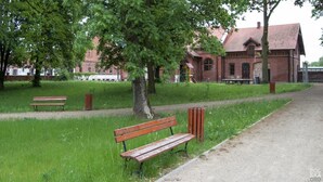 A park with benches and a brick building in the background. - Holiday Home on Lake Ostrowo Near Baltic Sea (gmina Wolin)