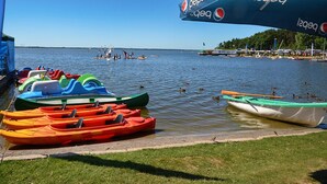 A lakeside area with colorful kayaks and a Pepsi-branded umbrella. - Holiday Home Near Dabki Beach (Darlowo)