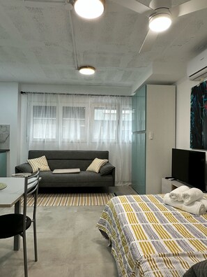 Relax in this stylish room with a comfortable sofa, flat-screen TV, and a neatly made bed.