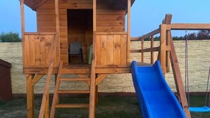 A wooden playhouse with a slide and a ladder leading to an entrance. - Large Holiday Villa With Summer Pool and Sauna (gmina Sianów)