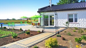 A house with a swimming pool, outdoor seating, and a garden. - Large Holiday Villa With Summer Pool and Sauna (gmina Sianów)