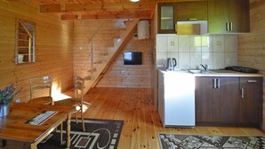 A wooden cabin interior with a kitchen, dining area, and a staircase. - Wooden House in Lubin by Lake Wicko (Międzyzdroje)