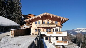 A large wooden chalet with a balcony, surrounded by snow-covered trees and mountains in the background. - Apartment in Fugenberg Near Spieljochbahn (Fuegenberg)