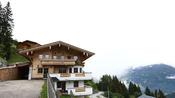 A two-story wooden chalet with a balcony, set against a mountainous backdrop. - Apartment in Fugenberg Near Spieljochbahn (Fuegenberg)