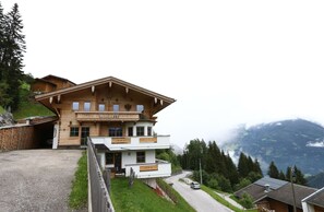A two-story wooden chalet with a balcony, set against a mountainous backdrop. - Apartment in Fugenberg Near Spieljochbahn (Fuegenberg)