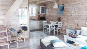 A cozy cabin interior with a staircase, a dining area, a sofa, and a kitchen. - Blue Lagoon - Vacation Home in Nowe Warpno (Nowe Warpno)