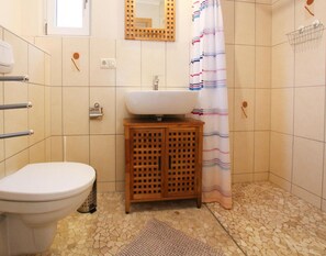 Bathroom features a white toilet, sink, and shower area with a striped curtain.